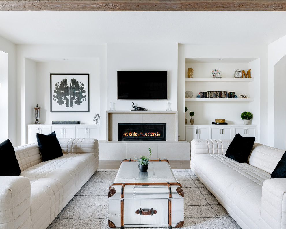 Diseño de sala de estar cerrada mediterránea con paredes blancas, suelo de madera clara, chimenea lineal, televisor colgado en la pared y alfombra