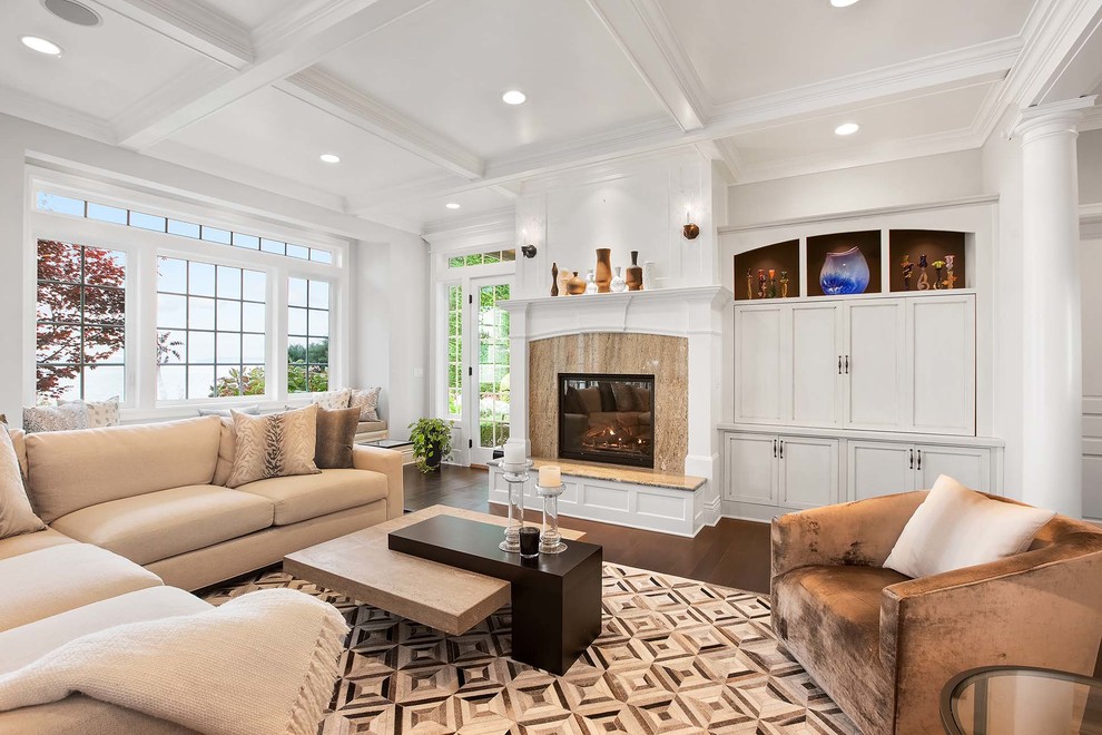 Imagen de sala de estar clásica con paredes blancas, suelo de madera oscura, todas las chimeneas, televisor retractable, suelo marrón y alfombra