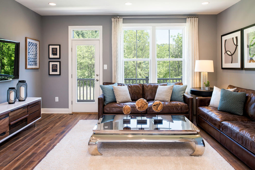 Diseño de sala de estar clásica renovada con paredes grises, suelo de madera oscura, televisor colgado en la pared y suelo marrón