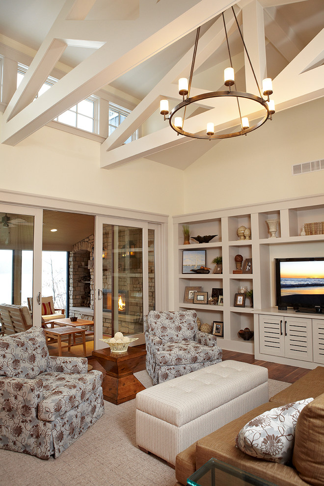 Idée de décoration pour un salon champêtre ouvert avec un mur beige, un sol en bois brun et un téléviseur encastré.