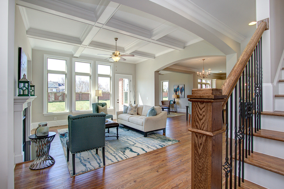 Großes, Offenes Klassisches Wohnzimmer mit grauer Wandfarbe, braunem Holzboden, Kamin, gefliester Kaminumrandung und TV-Wand in Charlotte