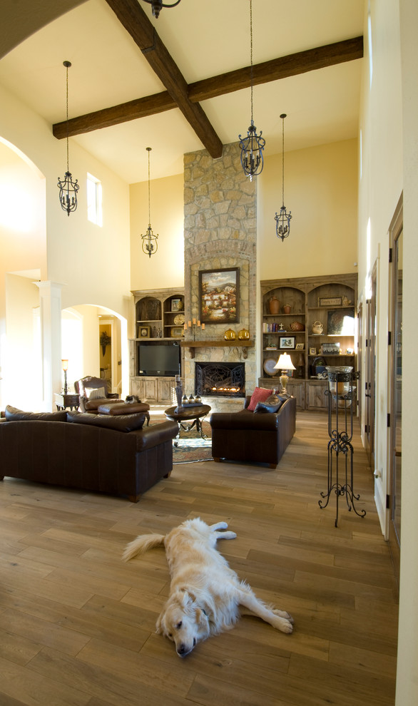 Ejemplo de sala de estar abierta mediterránea con paredes beige, suelo de madera clara, todas las chimeneas, marco de chimenea de piedra y pared multimedia