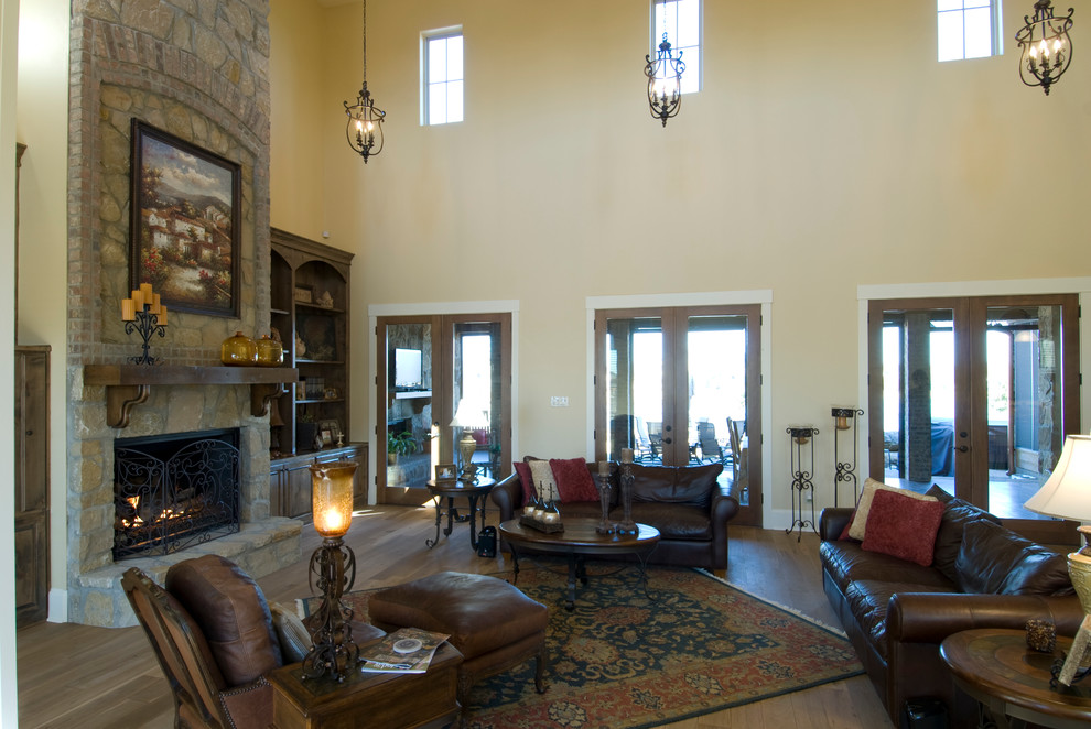 Design ideas for a mediterranean open plan games room in Austin with beige walls, light hardwood flooring, a standard fireplace, a stone fireplace surround and a built-in media unit.