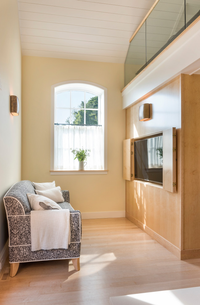 Cette photo montre une petite salle de séjour mansardée ou avec mezzanine chic avec un mur beige, parquet clair, un téléviseur dissimulé et un sol beige.