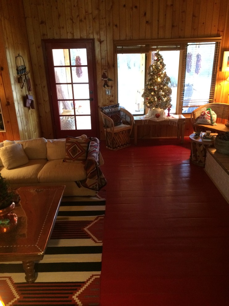 Modelo de sala de estar abierta de estilo americano grande sin televisor con paredes marrones, suelo de madera pintada, todas las chimeneas y suelo rojo
