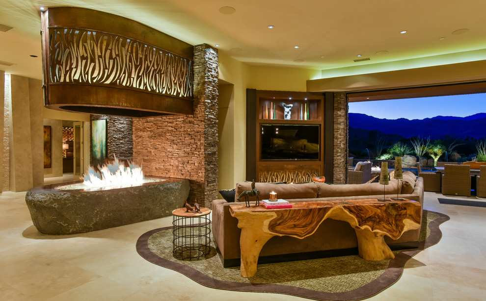 Imagen de sala de estar abierta contemporánea extra grande con paredes beige, suelo de travertino, chimenea de doble cara, marco de chimenea de piedra y pared multimedia