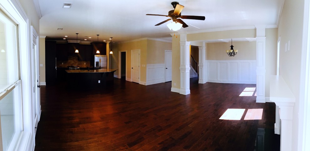 Geräumiges, Offenes Rustikales Wohnzimmer mit beiger Wandfarbe, dunklem Holzboden, Kamin und Kaminumrandung aus Holz in Sonstige