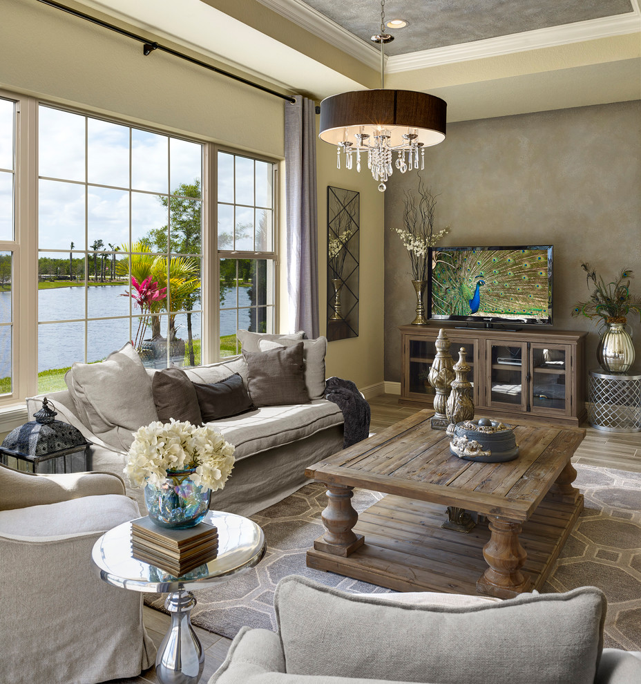 На фото: гостиная комната в средиземноморском стиле с бежевыми стенами, отдельно стоящим телевизором и коричневым полом