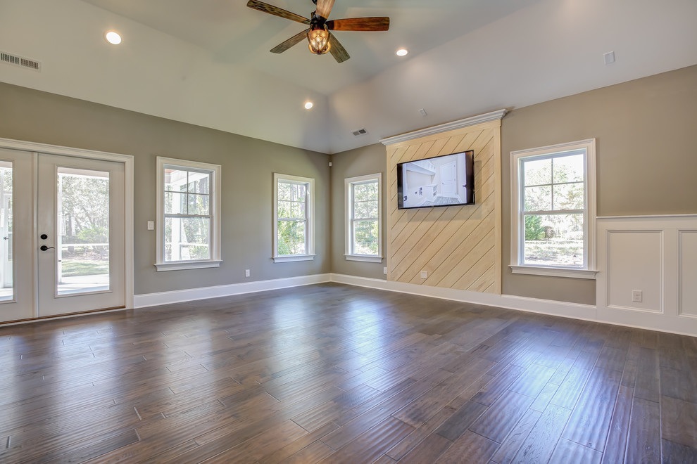 Ejemplo de sala de estar abierta tradicional renovada grande con paredes grises, suelo de madera oscura y televisor colgado en la pared