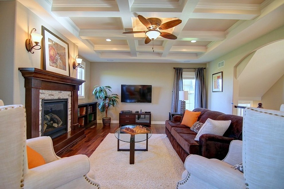 Mittelgroßes, Offenes Klassisches Wohnzimmer mit beiger Wandfarbe, braunem Holzboden, Kamin, Kaminumrandung aus Stein und TV-Wand in Milwaukee
