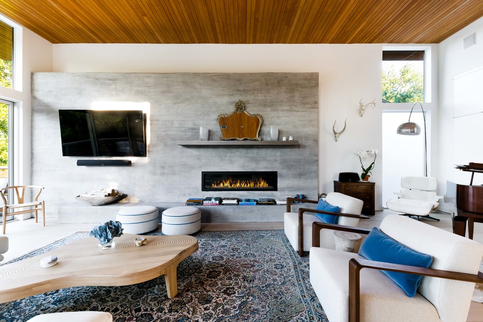 Diseño de salón actual con paredes grises, chimenea lineal, televisor colgado en la pared y suelo de madera clara