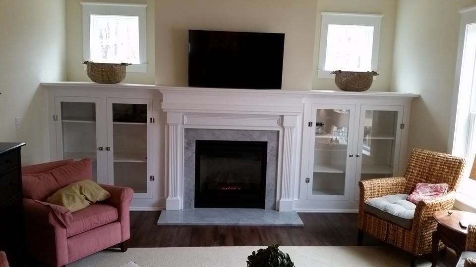 Imagen de sala de estar campestre con paredes beige, suelo de madera en tonos medios, todas las chimeneas, marco de chimenea de piedra y televisor colgado en la pared