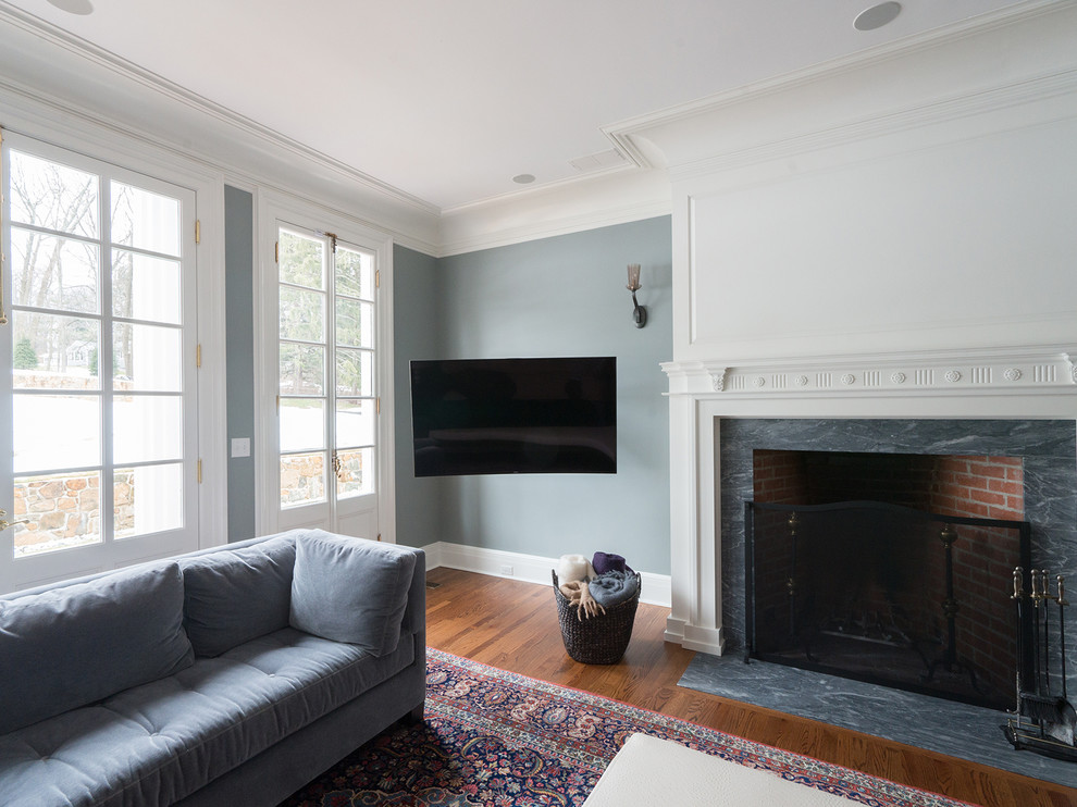 На фото: большая открытая гостиная комната в классическом стиле с синими стенами, паркетным полом среднего тона, стандартным камином и телевизором в углу