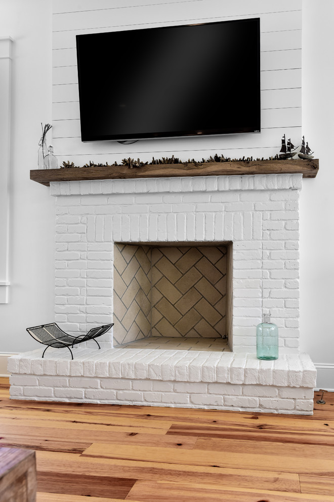 チャールストンにある中くらいなトラディショナルスタイルのおしゃれなオープンリビング (白い壁、無垢フローリング、標準型暖炉、レンガの暖炉まわり、壁掛け型テレビ、茶色い床) の写真