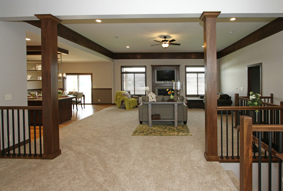 На фото: большая открытая гостиная комната в стиле неоклассика (современная классика) с серыми стенами, ковровым покрытием, стандартным камином, фасадом камина из плитки, телевизором на стене и бежевым полом