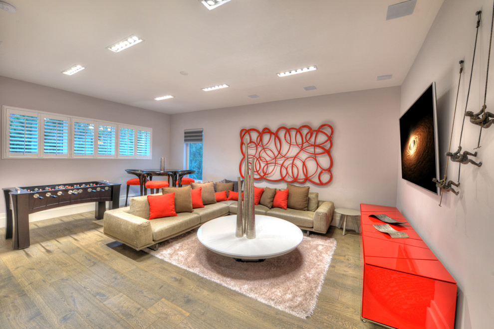 Esempio di un soggiorno design con sala giochi, pareti grigie, pavimento in legno massello medio, TV a parete e pavimento marrone