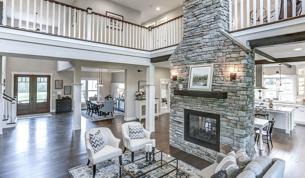 Ejemplo de sala de estar abierta de estilo de casa de campo extra grande con suelo de madera en tonos medios, chimenea de doble cara y marco de chimenea de piedra