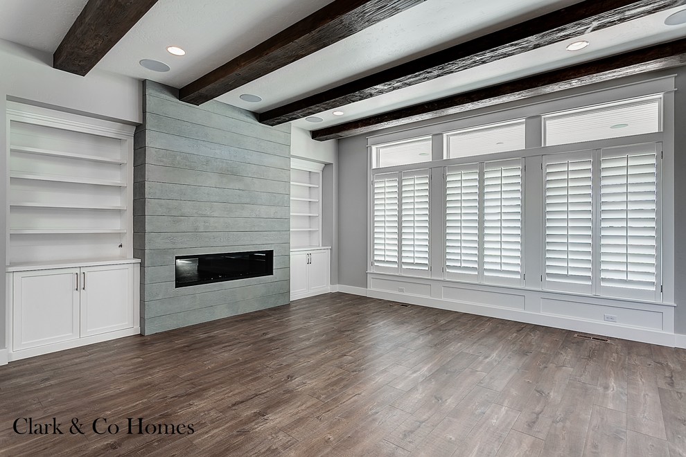 Large farmhouse dark wood floor family room photo in Boise with gray walls, a standard fireplace and a wall-mounted tv