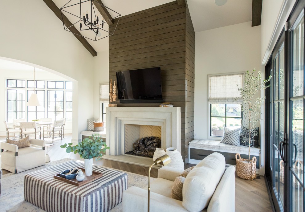 Imagen de sala de estar abierta clásica renovada grande con paredes blancas, suelo de madera en tonos medios, todas las chimeneas, marco de chimenea de hormigón, televisor colgado en la pared y suelo marrón