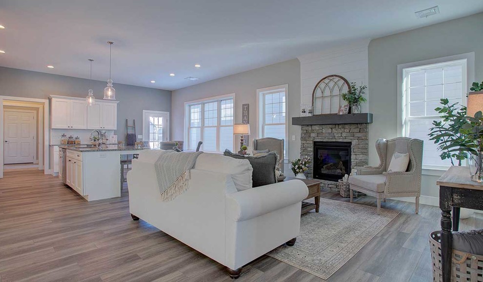 Ejemplo de sala de estar abierta de estilo americano grande con paredes grises, suelo de madera en tonos medios, todas las chimeneas y marco de chimenea de piedra