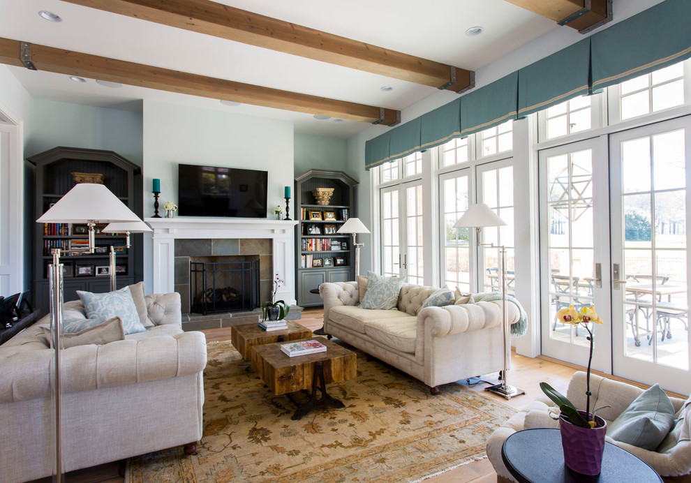 Foto de sala de estar clásica con paredes azules, suelo de madera en tonos medios, todas las chimeneas, marco de chimenea de baldosas y/o azulejos y televisor colgado en la pared