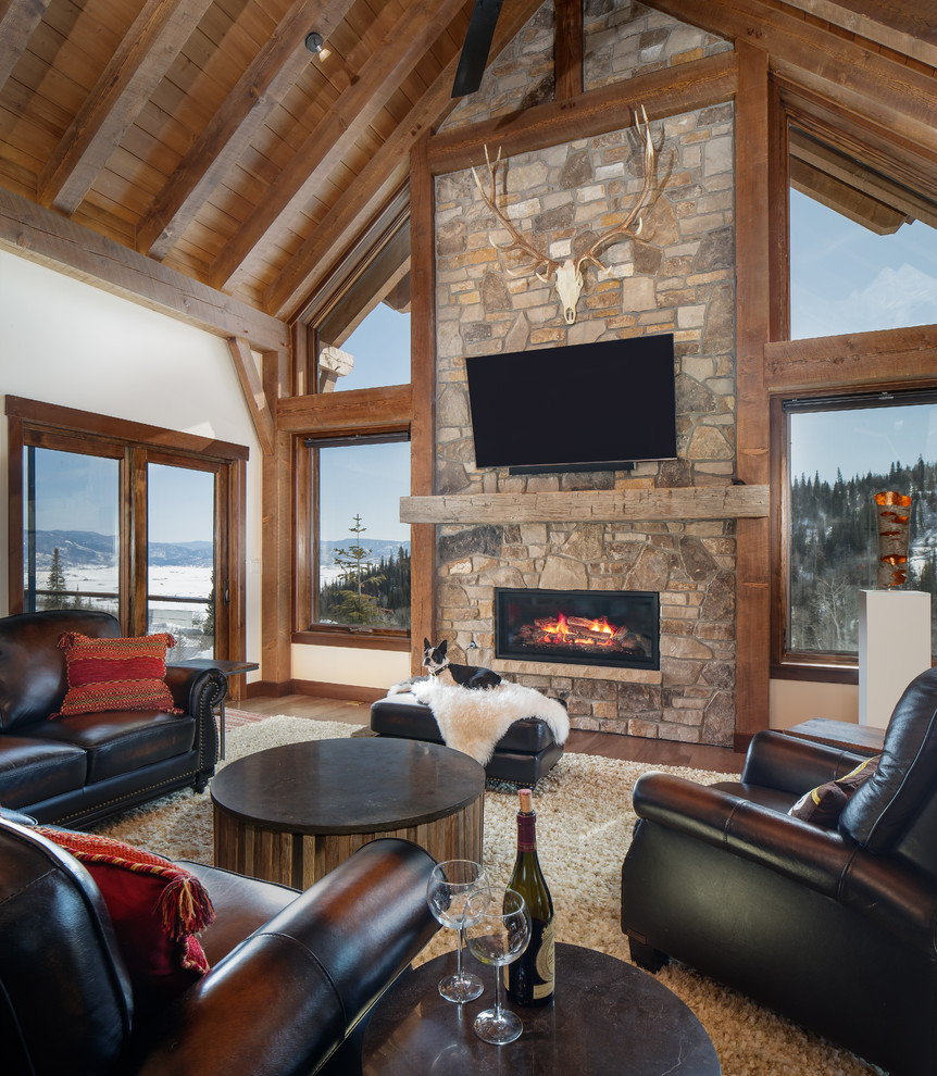 This is an example of a rustic games room in Denver with white walls, medium hardwood flooring, a ribbon fireplace, a stone fireplace surround and a wall mounted tv.