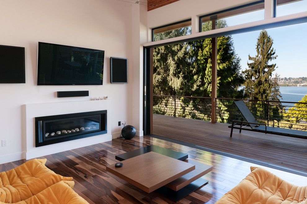 Cette image montre une grande salle de séjour design ouverte avec un mur blanc, un sol en bois brun et une cheminée ribbon.