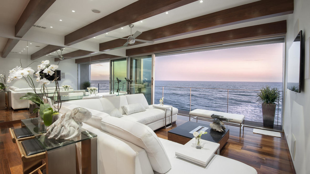 Example of a beach style open concept dark wood floor living room design in Los Angeles with white walls, no fireplace and a wall-mounted tv