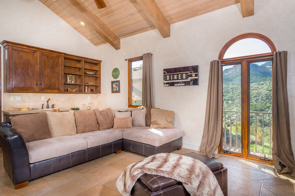 Modelo de sala de estar con barra de bar abierta mediterránea de tamaño medio sin chimenea con paredes beige, suelo de baldosas de terracota, pared multimedia y suelo beige