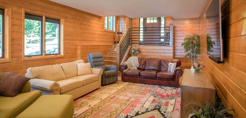 Cette photo montre une salle de séjour montagne avec un sol en bois brun et un téléviseur fixé au mur.