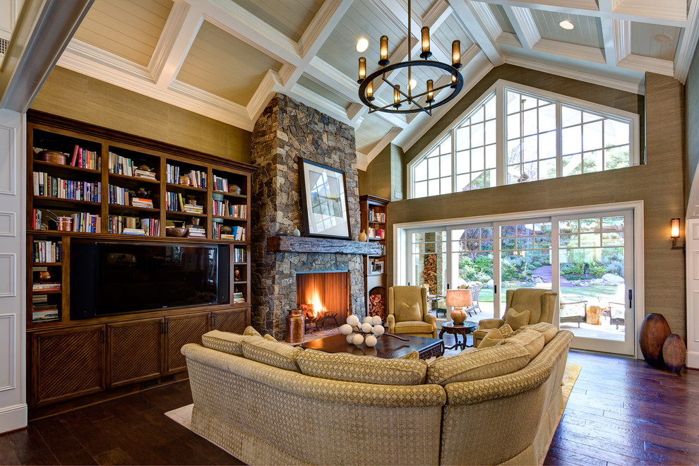 Inspiration for a large timeless open concept dark wood floor and brown floor family room library remodel in Orange County with beige walls, a standard fireplace, a stone fireplace and a media wall