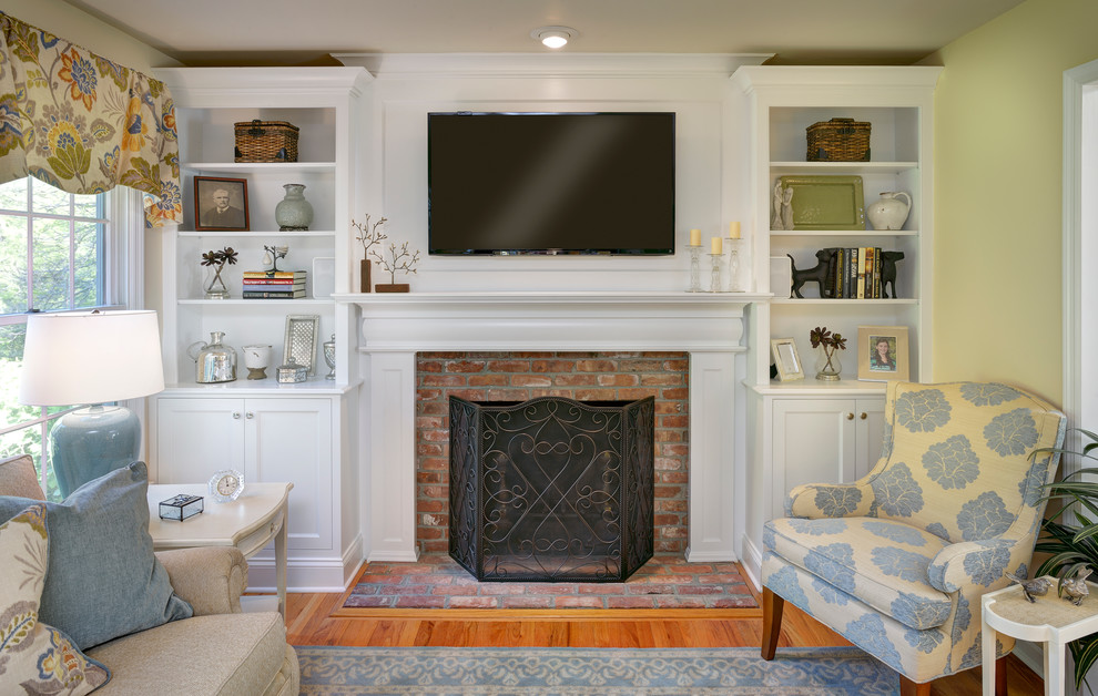 Example of a mid-sized transitional open concept medium tone wood floor and brown floor family room design in New York with a wall-mounted tv, beige walls, a standard fireplace and a wood fireplace surround