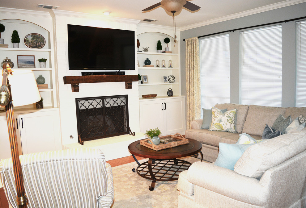 На фото: открытая гостиная комната среднего размера в классическом стиле с синими стенами, полом из ламината, стандартным камином, фасадом камина из кирпича, телевизором на стене и коричневым полом