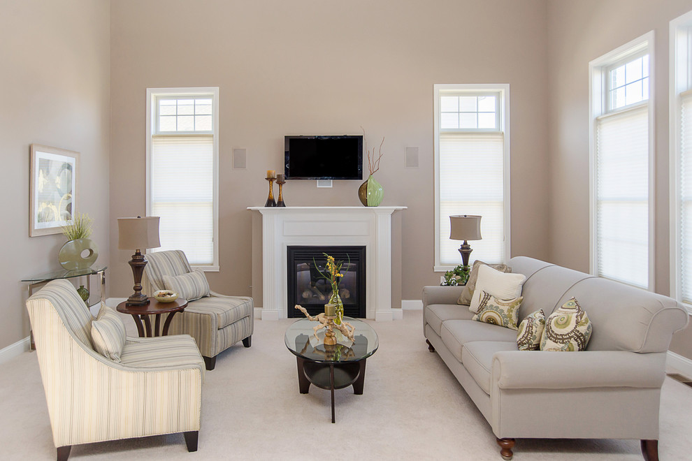 Immagine di un soggiorno classico con pareti beige, moquette, camino classico e TV a parete