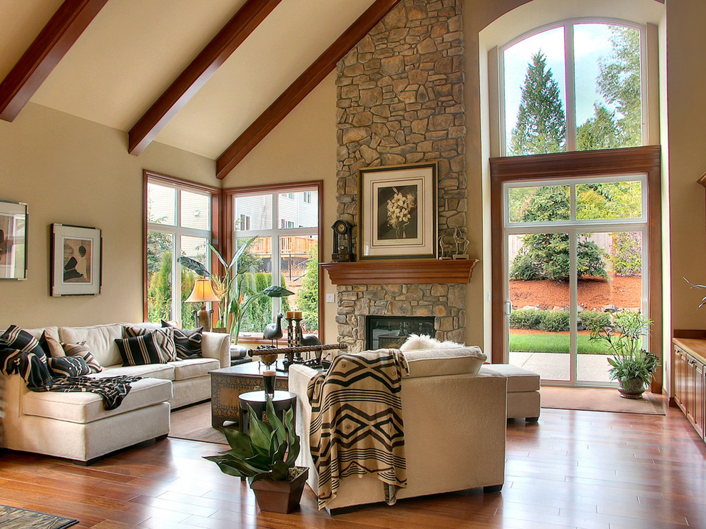 Imagen de sala de estar clásica con paredes beige, suelo de madera en tonos medios, todas las chimeneas y marco de chimenea de piedra