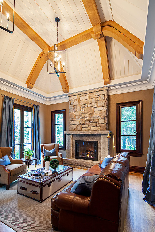 На фото: гостиная комната в классическом стиле с фасадом камина из камня с