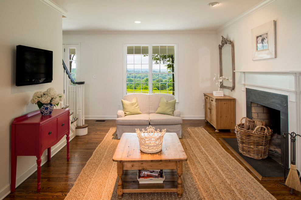 Klassisches Wohnzimmer mit beiger Wandfarbe, braunem Holzboden, Kamin, Kaminumrandung aus Stein und TV-Wand in Baltimore
