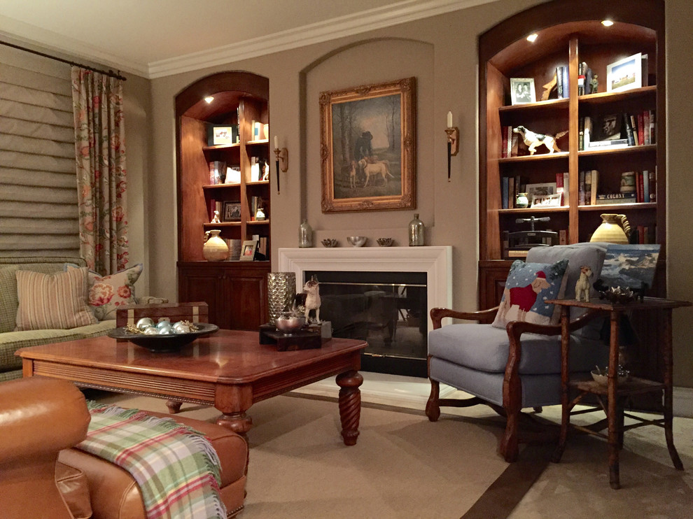 Cette image montre une grande salle de séjour traditionnelle fermée avec une bibliothèque ou un coin lecture, un mur marron, un sol en travertin, une cheminée standard, un manteau de cheminée en plâtre et un téléviseur dissimulé.