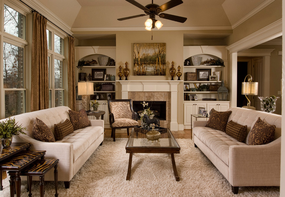 Immagine di un soggiorno classico con pareti beige, pavimento in legno massello medio, camino classico, cornice del camino in pietra e nessuna TV