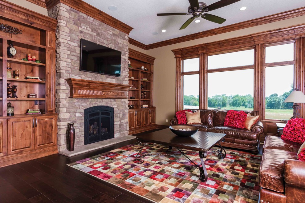 Imagen de sala de estar tradicional con paredes beige, suelo de madera oscura, todas las chimeneas, marco de chimenea de piedra y televisor colgado en la pared