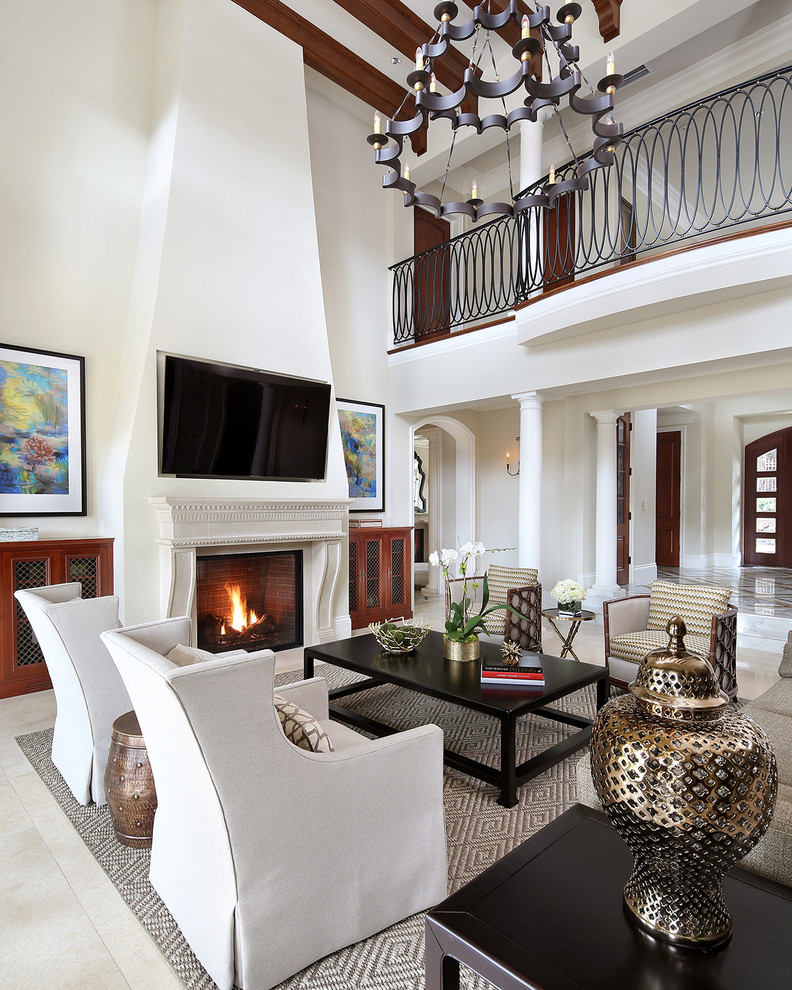 Пример оригинального дизайна: открытая гостиная комната в классическом стиле с белыми стенами, стандартным камином, фасадом камина из камня, телевизором на стене и бежевым полом