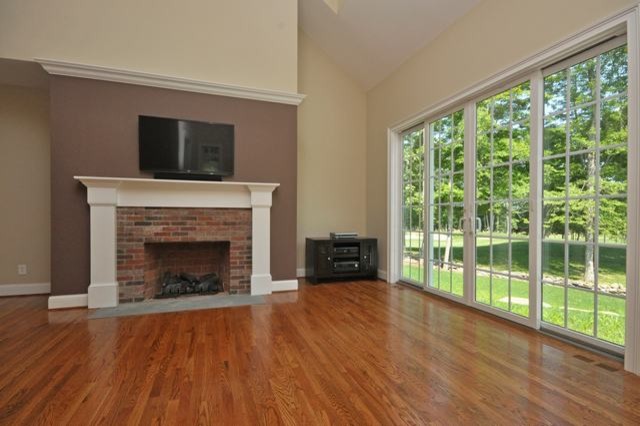 Small elegant open concept medium tone wood floor and brown floor family room photo in Bridgeport with beige walls, a standard fireplace, a brick fireplace and a wall-mounted tv
