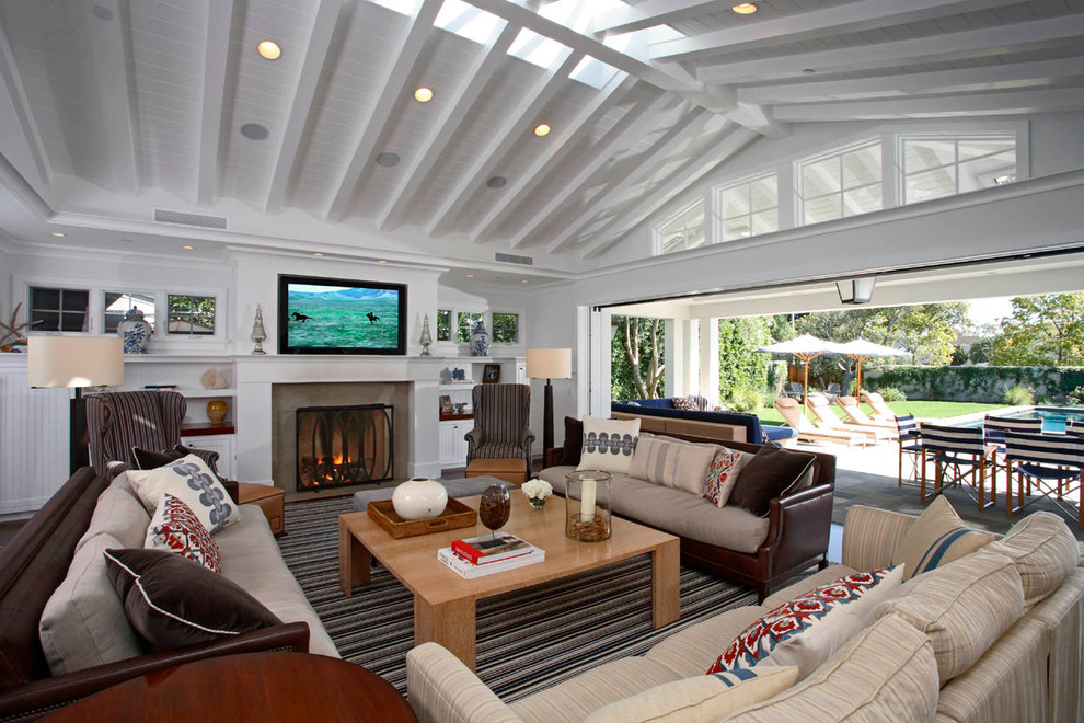 Immagine di un grande soggiorno tradizionale aperto con pareti bianche, camino classico e TV a parete