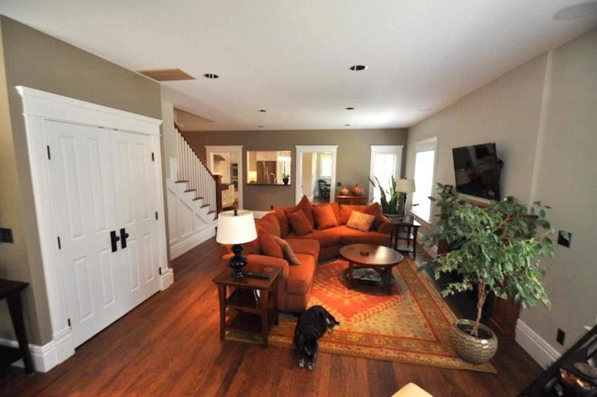 Cette photo montre une salle de séjour chic de taille moyenne et fermée avec un mur beige, un sol en bois brun, une cheminée standard, un manteau de cheminée en bois et un téléviseur fixé au mur.