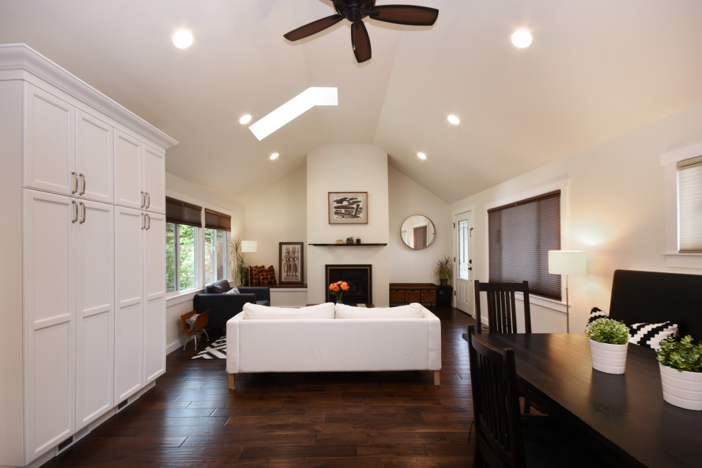 This is an example of a medium sized classic open plan games room in Seattle with white walls, dark hardwood flooring, a standard fireplace, a plastered fireplace surround, no tv and brown floors.