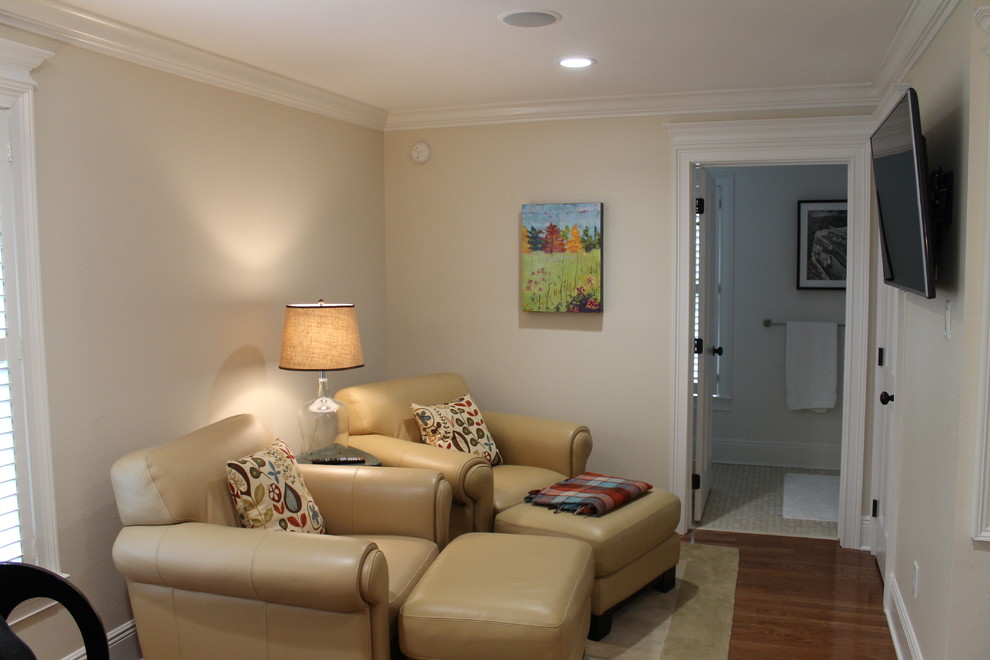 Imagen de sala de estar abierta clásica de tamaño medio sin chimenea con paredes beige, suelo de madera en tonos medios y televisor colgado en la pared