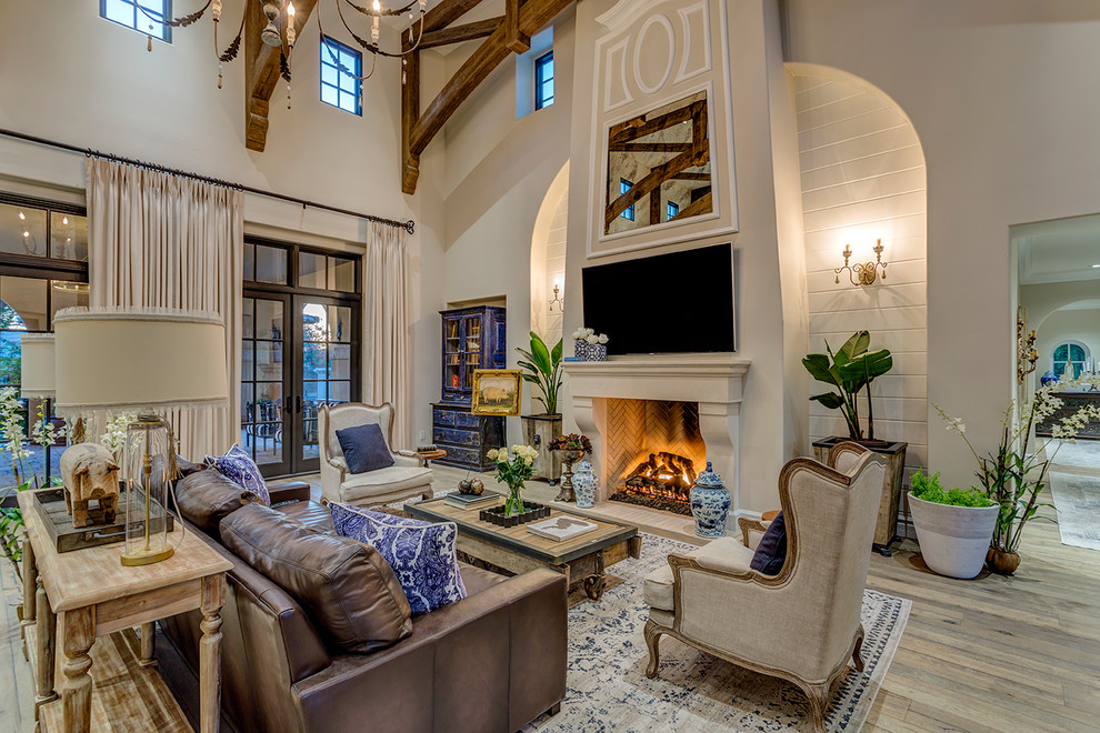 Inspiration for a french country light wood floor and beige floor family room remodel in Phoenix with beige walls, a standard fireplace and a wall-mounted tv