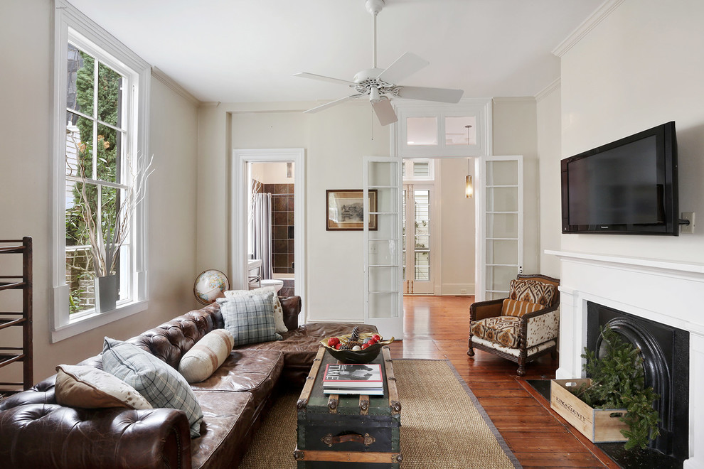 Mittelgroßes, Abgetrenntes Klassisches Wohnzimmer mit beiger Wandfarbe, braunem Holzboden, Kamin, TV-Wand, Kaminumrandung aus Holz und braunem Boden in Charleston