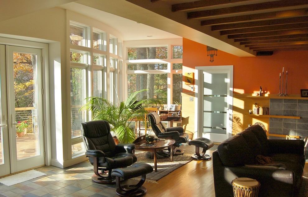На фото: двухуровневая гостиная комната среднего размера в современном стиле с с книжными шкафами и полками, разноцветными стенами, полом из сланца, стандартным камином, фасадом камина из камня и скрытым телевизором