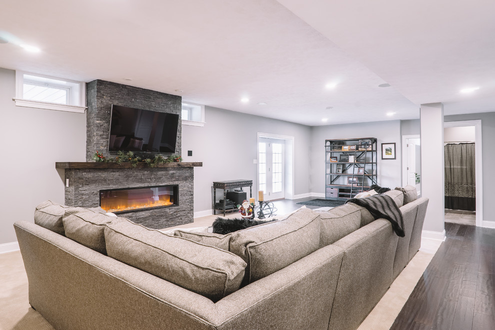 Inspiration for a large transitional open concept dark wood floor family room remodel in Other with gray walls, a standard fireplace, a stone fireplace and a wall-mounted tv